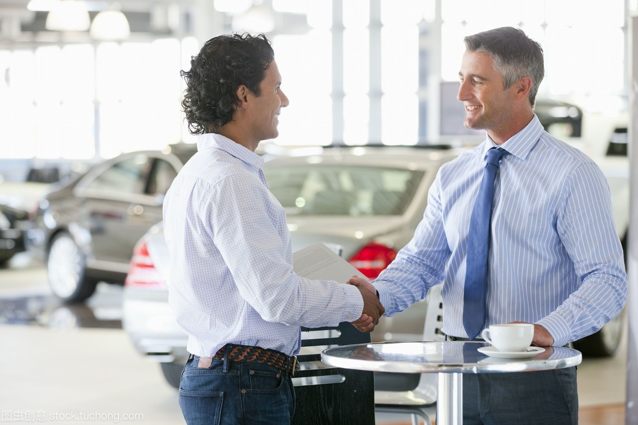销售人员和顾客在汽车经销商展厅的桌子上握手